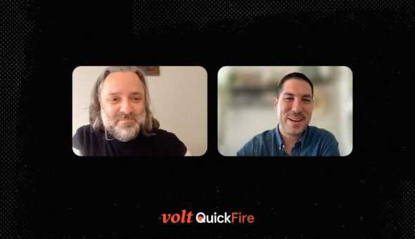 A graphic design showing two people's faces talking to each other online. Both are white men, one with long gray hair and a gray beard, the other with short black hair. They are both smiling. The two images of their faces are set against a black background with the stylized words 'Volt QuickFire' beneath the images of their faces.