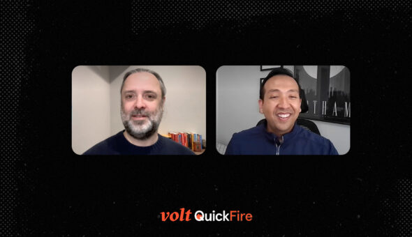 Side-by-side images of two people speaking to each other remotely, the man on the left has grey hair, a grey beard, and light skin; the man on the right has darker skin and black hair. Their two frames are set against a black background, at the bottom of which are the words Volt QuickFire in stylized orange and white lettering.