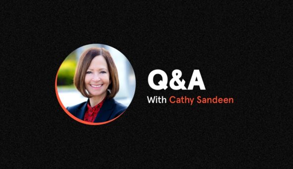 A light skinned woman with short brown hair in a black blaze and red shirt set against a black background with the words Q&A Virtual Interview with Cathy Sandeen.